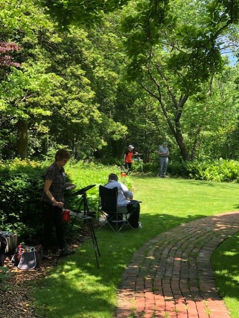 Photo of plein air painters in a green landscape with a winding path