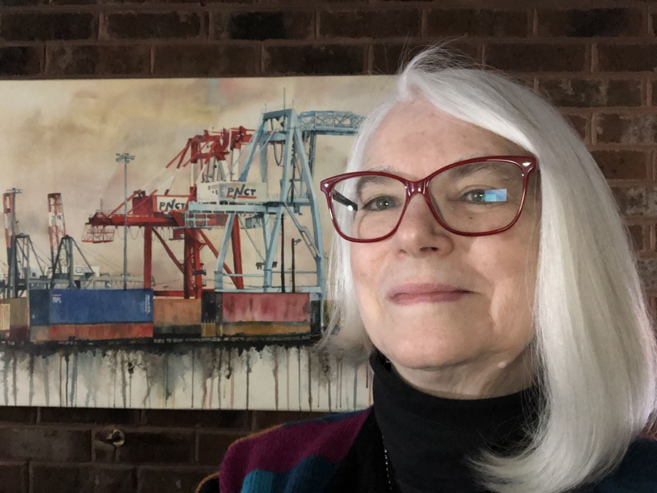 Photograph of April Rimpo standing in front of one of her paintings
