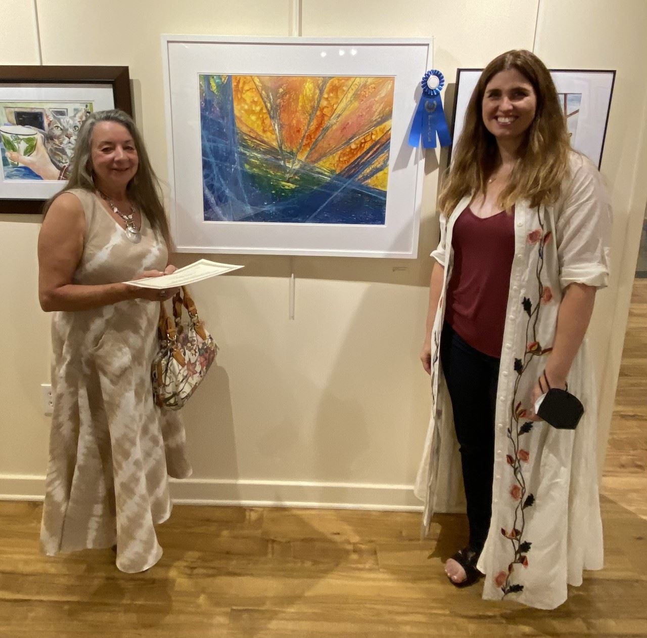 Photo of Artist and Juror standing together with framed painting and blue ribbon